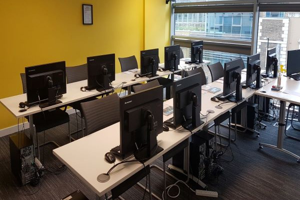 An office with rows of desks and desktop monitors set up for a corporate training event