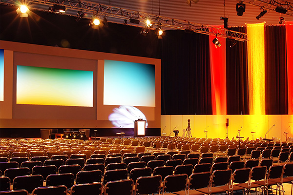 Rows of chairs in front of a large stage set up for a corporate conference