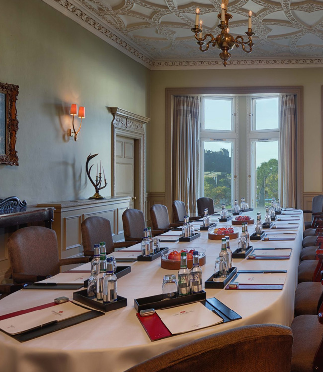 Long table with empty seats in a hotel set up for a meeting
