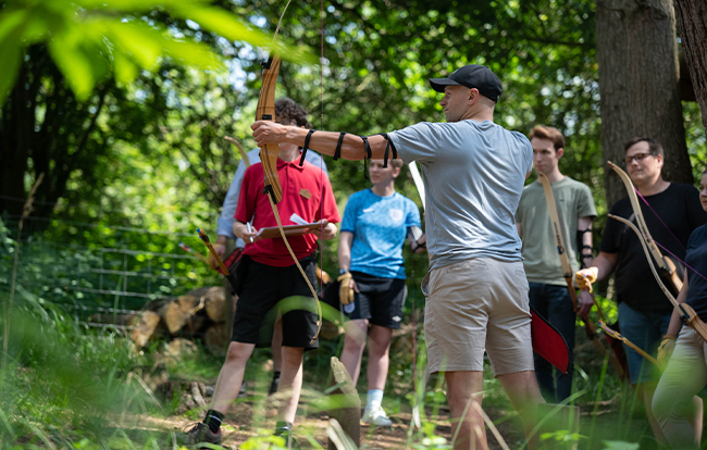 Man outside with a bow and arrow at a corporate team building event